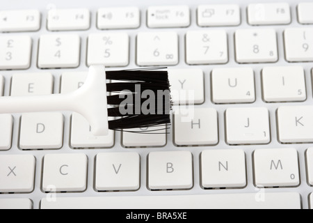 cleaning a computer laptop keyboard with a small plastic brush Stock Photo