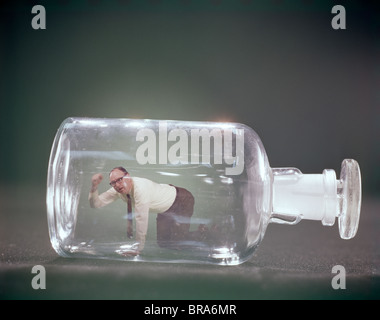 1960s ANGRY MAN ON HANDS & KNEES TRAPPED INSIDE BOTTLE Stock Photo