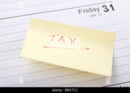 post-it note regarding tax bill reminder stuck into a diary at the end of the month Stock Photo