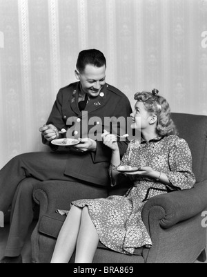 1940s SMILING COUPLE EATING DESSERT MAN IN ARMY UNIFORM Stock Photo