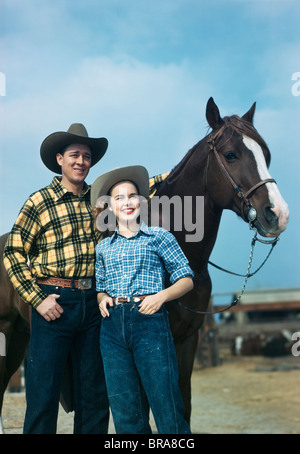 1940s 1950s TEEN COUPLE IN WESTERN WEAR STANDING BY HORSE SMILING Stock Photo