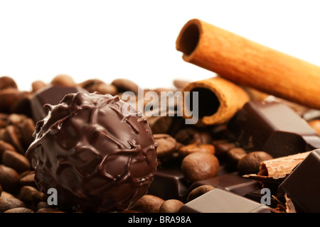 plain truffle praline in front of cinnamon sticks and coffee beans on a plain chocolate bar Stock Photo
