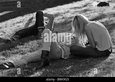 1960s 1970s HIPPIE COUPLE WOMAN WITH LONG BLONDE HAIR SIT BESIDE MAN LYING IN GRASS Stock Photo