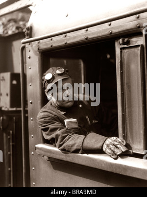 1920s 1930s 1940s RAILROAD TRAIN ENGINEER LOOKING OUT WINDOW OF LOCOMOTIVE CAB DRIVING THE STEAM ENGINE Stock Photo