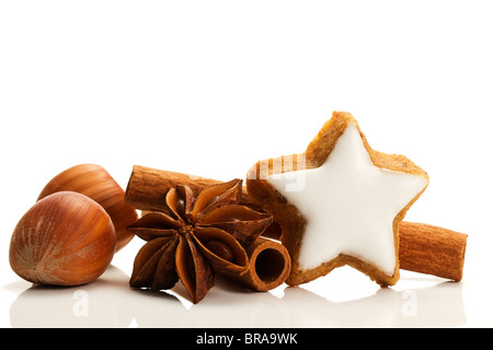 star shaped cinnamon biscuit with cinnamon sticks and hazelnuts on white background Stock Photo