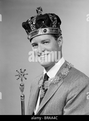 1950s PORTRAIT OF MAN WEARING A KING'S CROWN AND HOLDING A SCEPTER WHILE SMILING Stock Photo