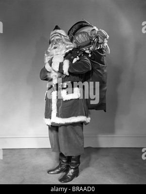 A Santa Claus carrying a bag full of gifts on his back isolated on ...