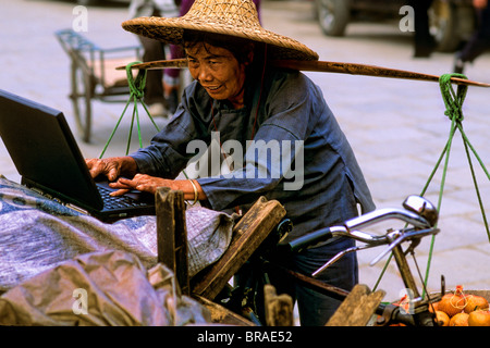 Old Chinese woman vendor on laptop in Yangshou China Stock Photo