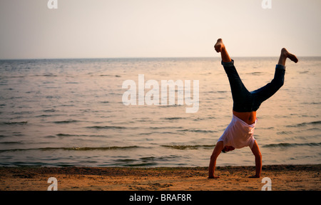 man doing handstand on sunset beach Stock Photo