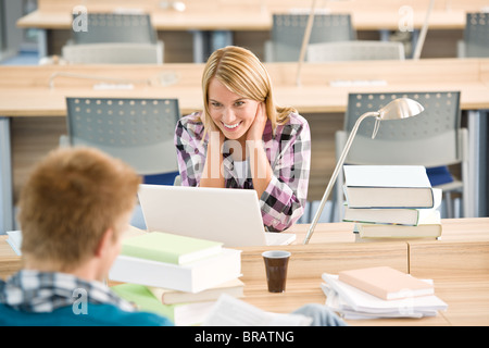 Two students with books and laptop in classroom studying Stock Photo
