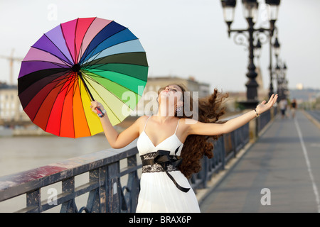 french woman walking on bridge "pont de pierre" holding rainbow umbrella in Bordeaux, France Stock Photo
