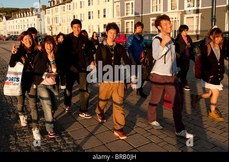 A group of happy smiling Chinese foreign overseas university students on Aberystwyth promenade, Wales UK Stock Photo