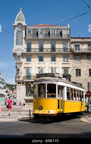A vintage Lisbon tram passed through the Largo de Chaido in Lisbon. An ornate building typical of Lisbon provides the background Stock Photo