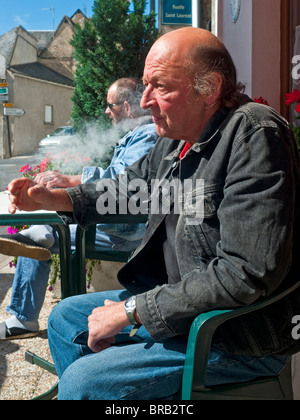 Man smoking at table outside bar - France. Stock Photo