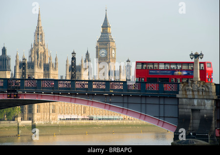 A London bus crossing Lambeth bridge over the Thames river with the Palace of Westminster in the background. London, England. Stock Photo