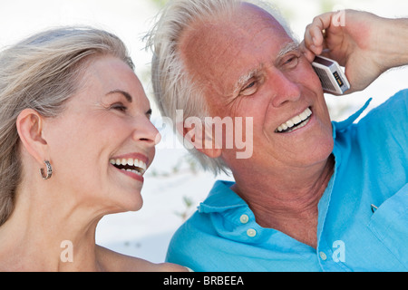 Happy senior man and woman couple laughing while talking on a mobile cell phone Stock Photo
