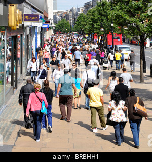 Crowd of shoppers & tourists view from above walking on busy Oxford Street pavement famous West End shopping street & shop fronts summer day London UK Stock Photo