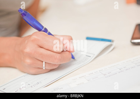 woman's hand writing checks Stock Photo