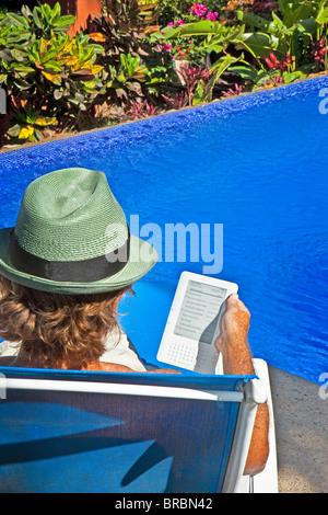 man reading e-book on chaise outdoors Stock Photo