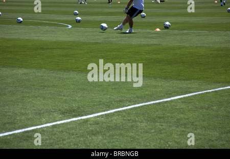 Footballers warm up pre-game on pitch Stock Photo