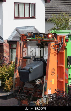 Bin men emptying household rubbish from wheelie bins into refuse truck in the street. Anglesey North Wales, UK, Britain. Stock Photo