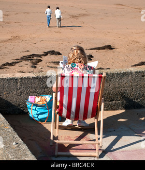 a young woman sitting in a deck chair at summerleaze beach, bude, cornwall Stock Photo