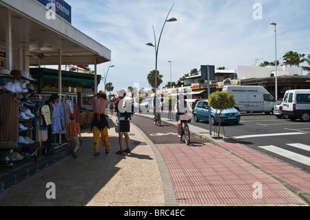 dh  PUERTO DEL CARMEN LANZAROTE Tourists shopping and tourist cyclists on pushbikes cycle path pavement Stock Photo
