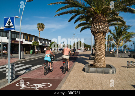 dh  PUERTO DEL CARMEN LANZAROTE Tourist couple cyclists on pushbikes cycle path pavement holiday spain couples bicycle riding cycles Stock Photo
