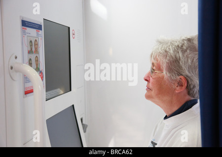 Senior woman posing in a passport photo booth preparing to travel abroad. England, UK, Britain. Stock Photo