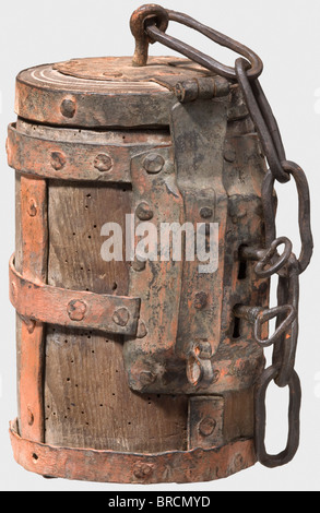 A heavy German money box, circa 1500 Cylindrical, turned oakwood case with intersecting iron straps. Hinged lid with slot, fastening chain and hasp. Riveted double lock on the side, with two keys. Red lead coat of later date, height 22 cm. The double lock with two keys suggests that this box was used as a guild box or for administrative purposes, as it could only be opened in the presence of two persons with corresponding keys. A very similar box with a double lock is depicted in Michael Trömner, Behältnisse für Kostbares 1500 - 1700, Abensberg 2006, pp. 30 f. , Stock Photo