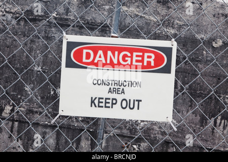 danger construction site sign mounted on fence surrounding construction Stock Photo