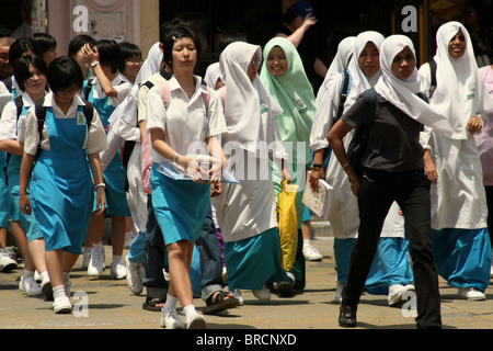 A group of students crosses a street after a day of classes in the Georgetown district of Penang, Malaysia. Stock Photo