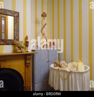 Yellow+white wide-striped wallpaper in nursery bedroom with baby's cot with white muslin trim Stock Photo