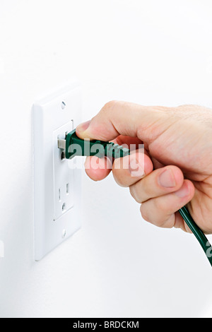 Hand inserting green electrical plug into outlet Stock Photo