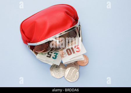 Studio, still life, UK, Europe. Red money purse containing ten and five pound notes with some coins spilling out Stock Photo