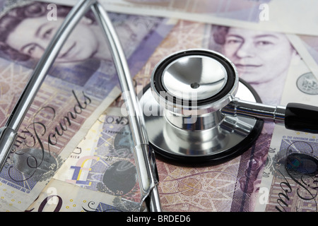 medical stethoscope on a pile of twenty pounds sterling banknotes Stock Photo