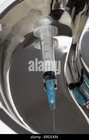 hypodermic syringe and needle in a metal kidney tray Stock Photo