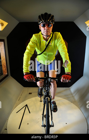 A test cyclist rides a road bike in a wind tunnel experiment for cycling clothing and racing bicycle design Stock Photo