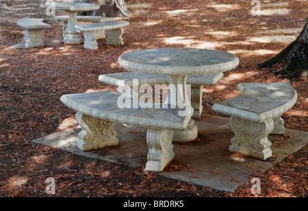 Concrete and stone Round Picnic tables in a wooded grove Stock Photo