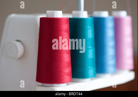 Multicolored spools of thread on a spindle on a serger sewing machine with pastel colors Stock Photo