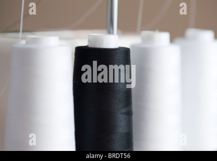 Black and white spools of thread on a serger sewing machine Stock Photo