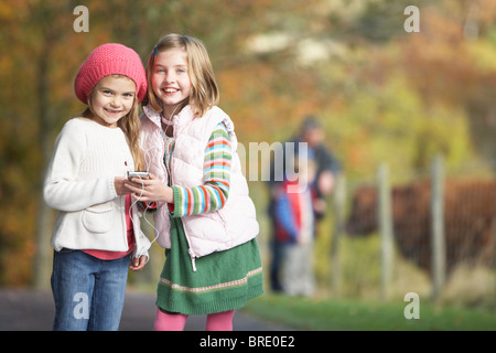 Two Young Girl Listening To MP3 Player Outdoors Stock Photo