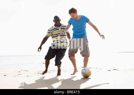 Two Young Men Palying Football On Beach Together Stock Photo