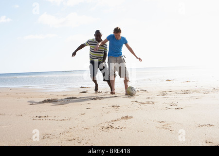 Two Young Men Palying Football On Beach Together Stock Photo