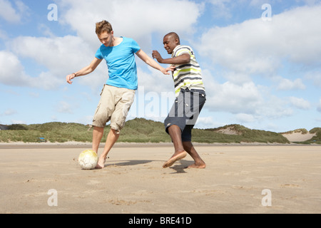 Two Young Men Palying Football On Beach Together Stock Photo