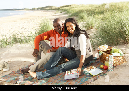 Young Couple Enjoying Picnic On Beach Together Stock Photo