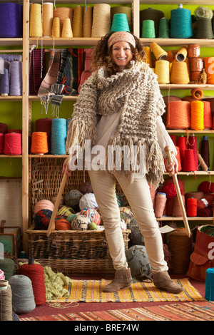 Woman Wearing Knitted Scarf Standing In Front Of Yarn Display Stock Photo