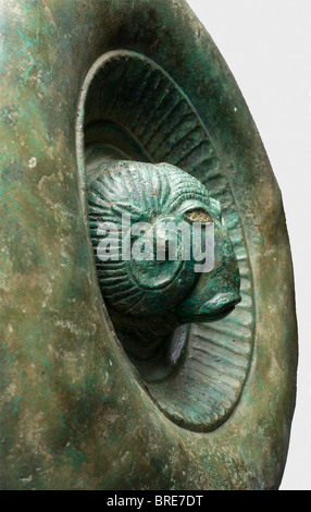 A decorative Etruscan shield, circa 500 B.C. Bronze. The separately made central medallion displays a ram's head in high relief with remnants of white eye inlays (colour paint?), surrounded by an ornamental ring bearing a tongue pattern, and a broad, strongly rounded protuding rim. Diameter 28.5 cm. Broken into small pieces, glued together and stabilised with fiberglass. Restorations at various places. Axel Guttmann Collection (R 203/AG 195). Shield-shaped plates of this kind appear in great quantities in Etruscan graves and are generally decorated with a lion , Stock Photo