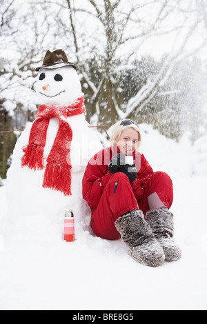 Teenage Girl Next To Snowman With Flask And Hot Drink Stock Photo