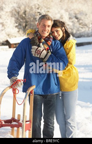 Young Couple Standing In Snowy Landscape Holding Sledge Stock Photo